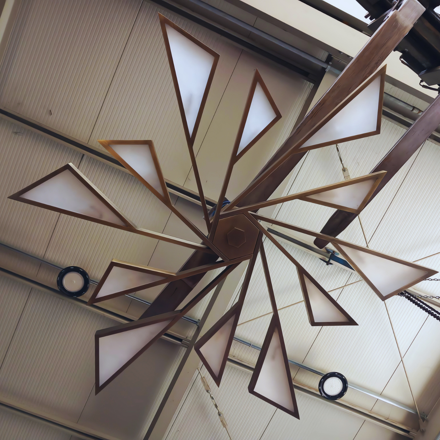 Custom-designed alabaster chandelier featuring a unique triangular pattern and warm lighting, displayed in a modern installation setting.