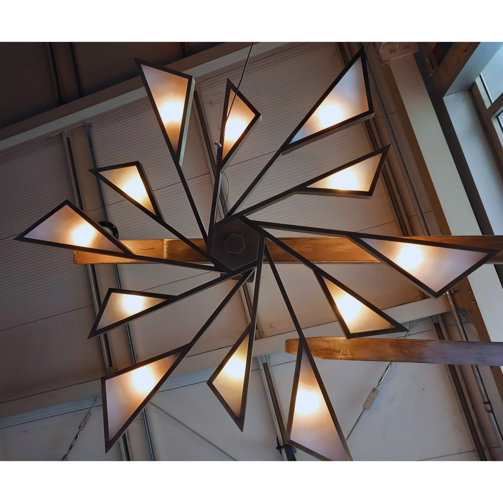 Custom-designed alabaster chandelier featuring a unique triangular pattern and warm lighting, displayed in a modern installation setting.