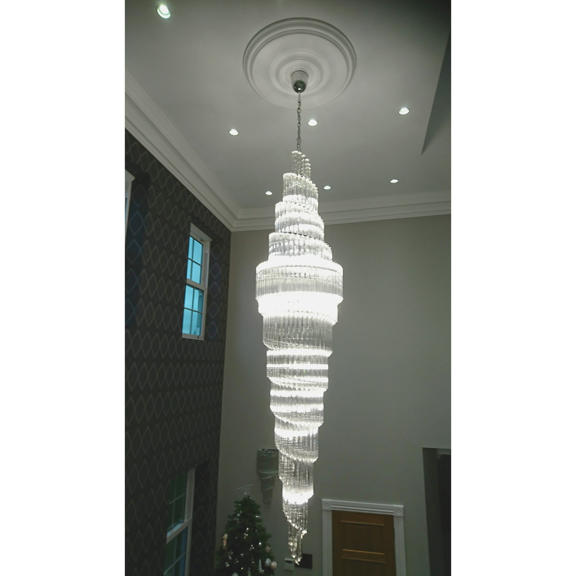 Close-up view of the spiral chandelier with layered glass design, glowing in a contemporary hallway.