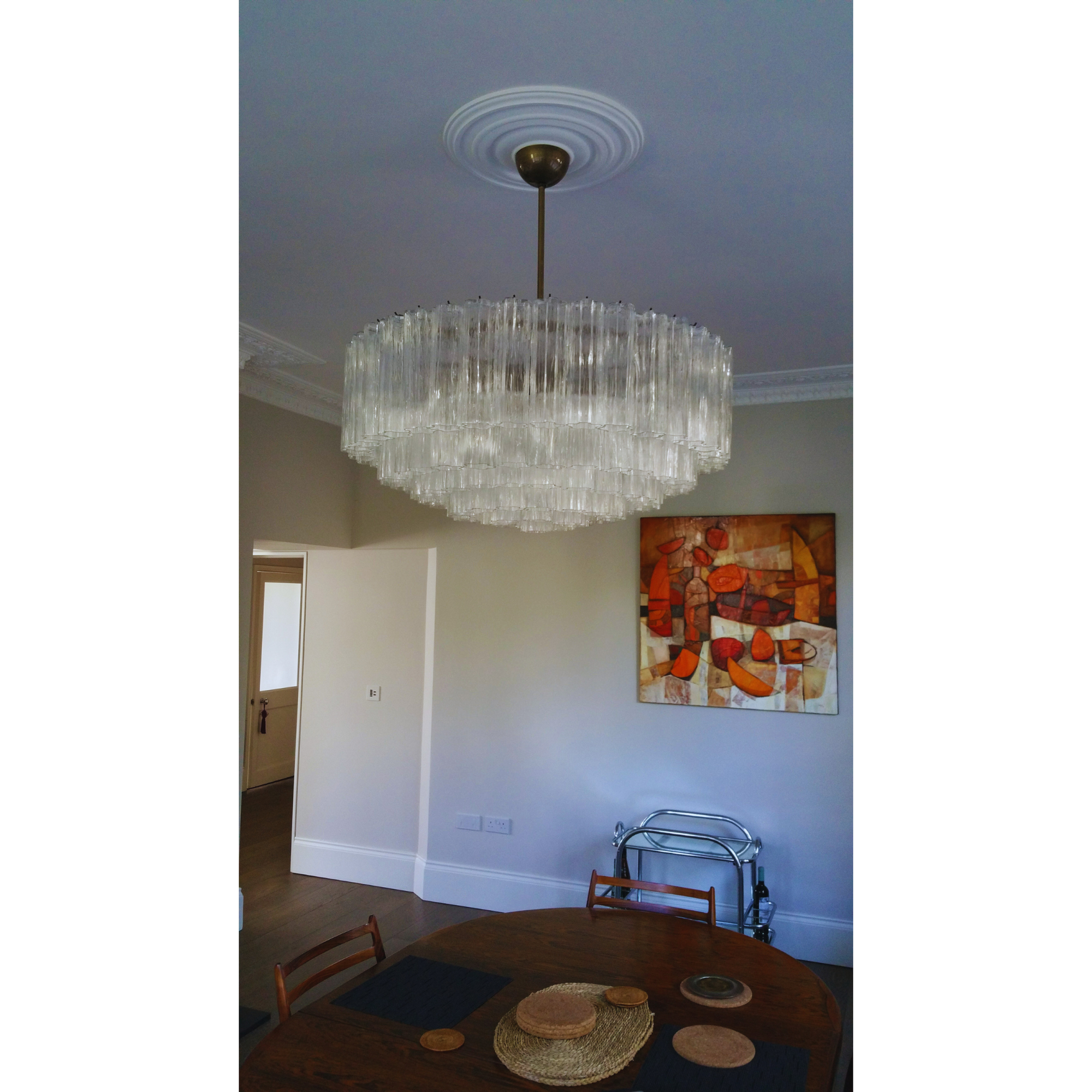 Full view of the Tronchi Drum Murano Glass Chandelier in a living room, showcasing its clear Murano glass "tronchi" elements.