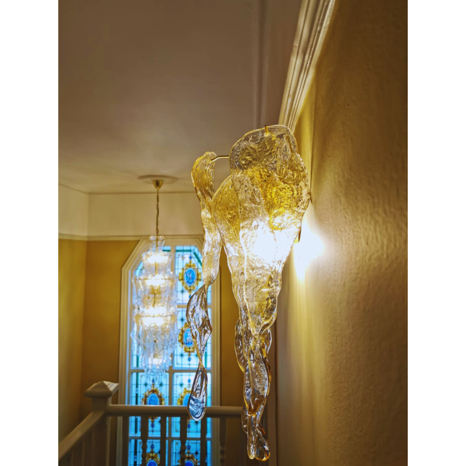 Close-up of amber and clear Murano glass chandelier against a decorative wallpapered wall