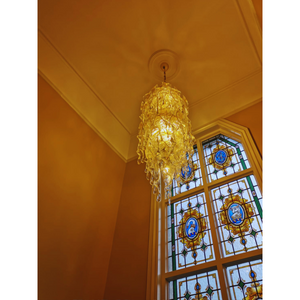 Golden amber Murano glass chandelier detail with intricate glass patterns near a stained glass window