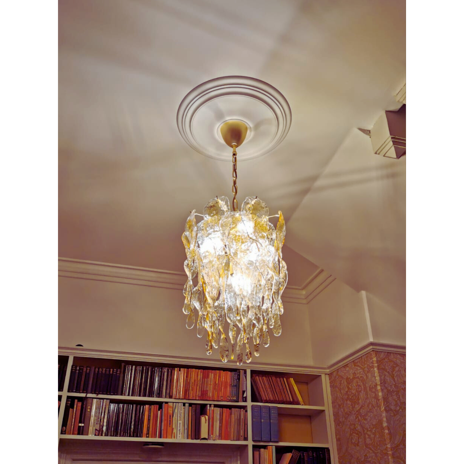 Amber-colored Murano glass chandelier detail hanging gracefully in a library setting