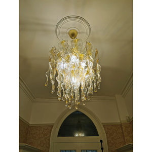 Amber Murano chandelier elegantly suspended from ceiling, enhancing entrance with warm light.