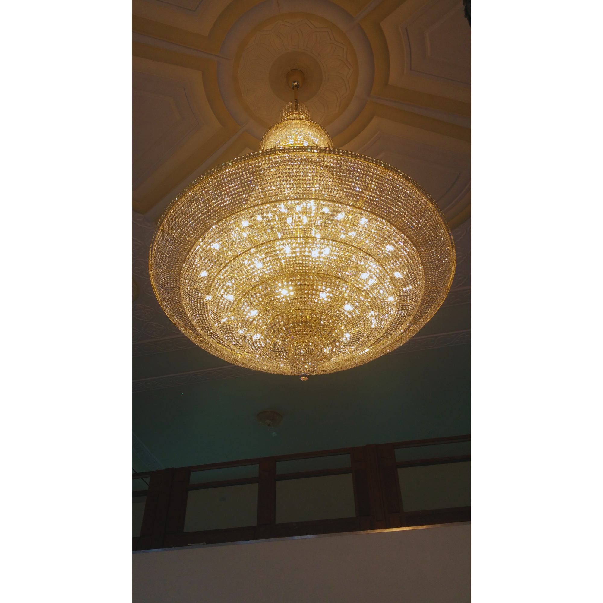 Close-up view of a grand mosque chandelier, installed with scaffolding setup.