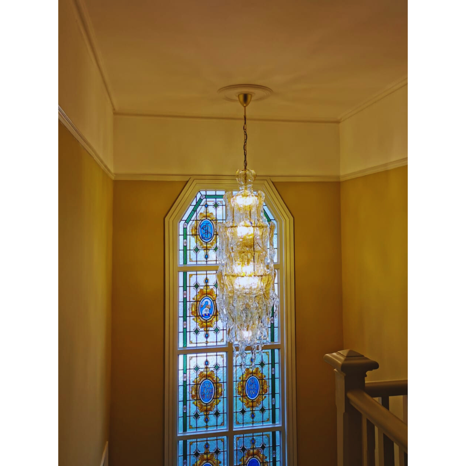 Murano glass wall sconce with amber details illuminating a luxurious stairwell area