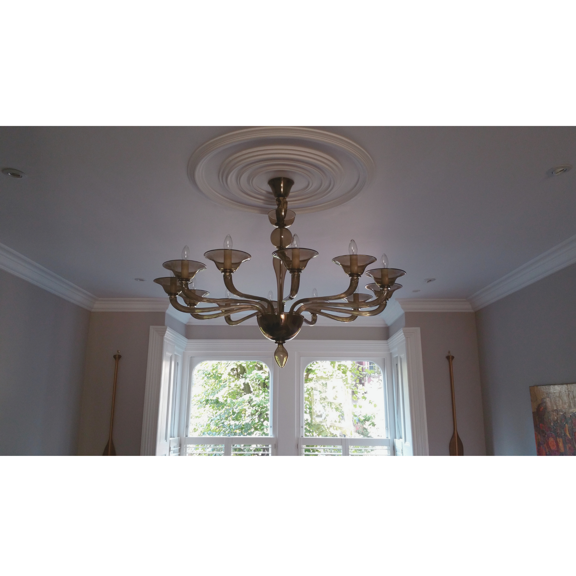 Wide-angle view of the chandelier in a bright room with detailed molding.