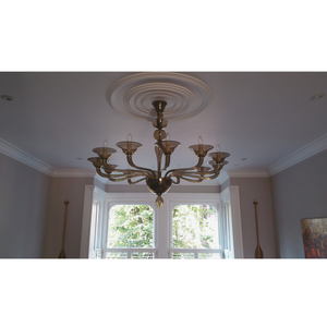 Wide-angle view of the chandelier in a bright room with detailed molding.