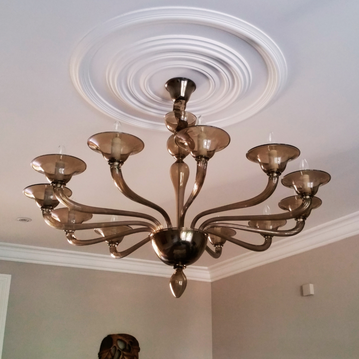 Side view of the chandelier highlighting its elegant smoke glass arms and warm tones.