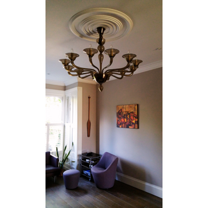 Chandelier displayed in a sophisticated living room with purple chairs and wall art.