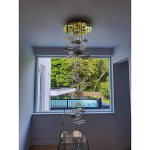 Modern bubble chandelier illuminated in a stairwell, with frosted and clear glass globes.