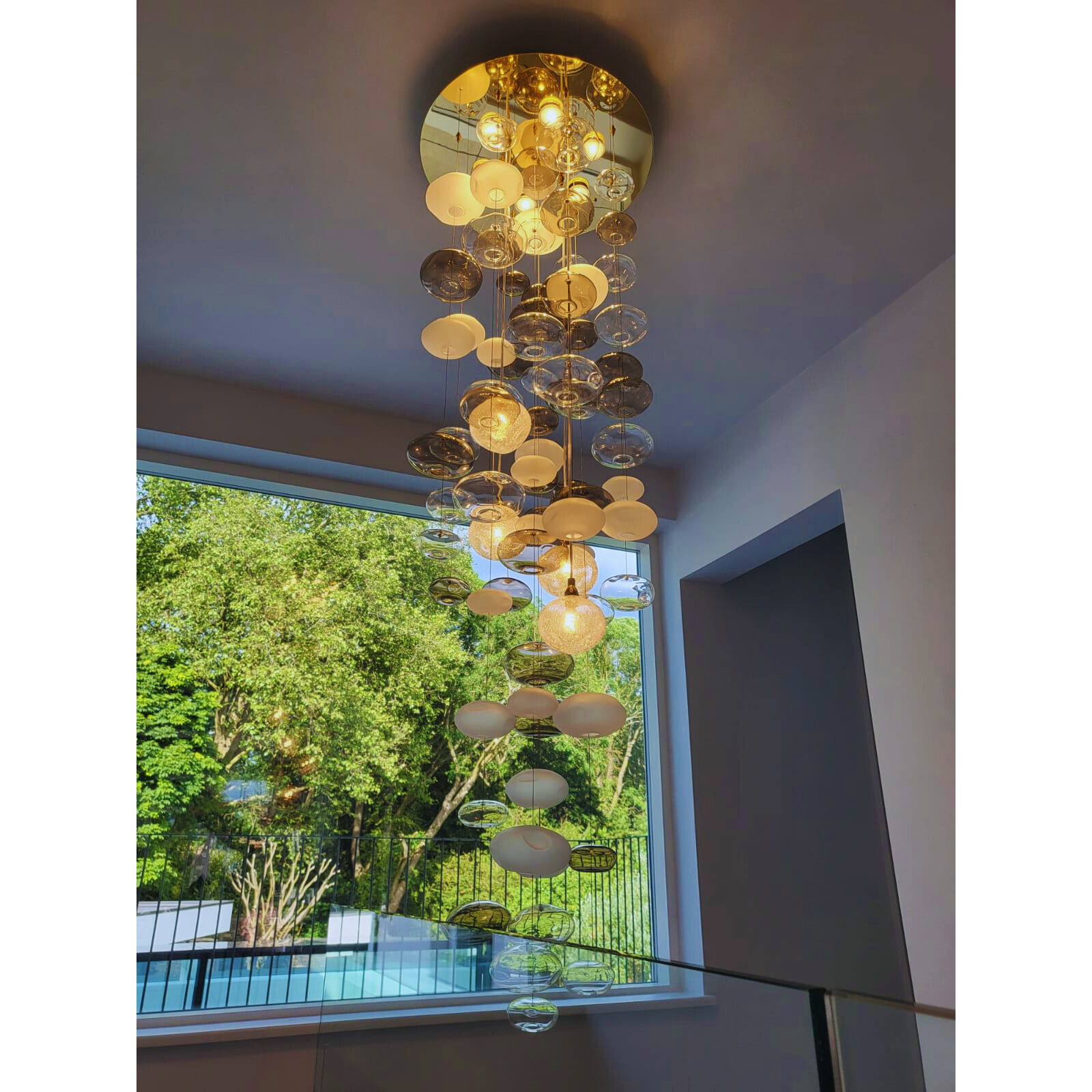 Golden ceiling mount with hanging frosted and clear bubble glass chandelier in a bright space.