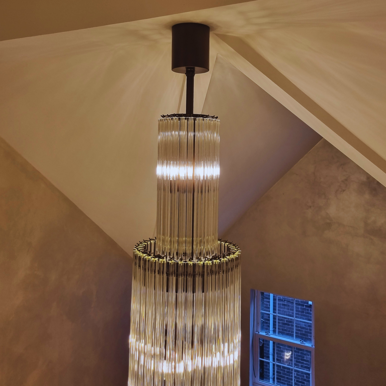 The Long Prism Chandelier illuminated in a grand staircase, highlighting its elegant design.