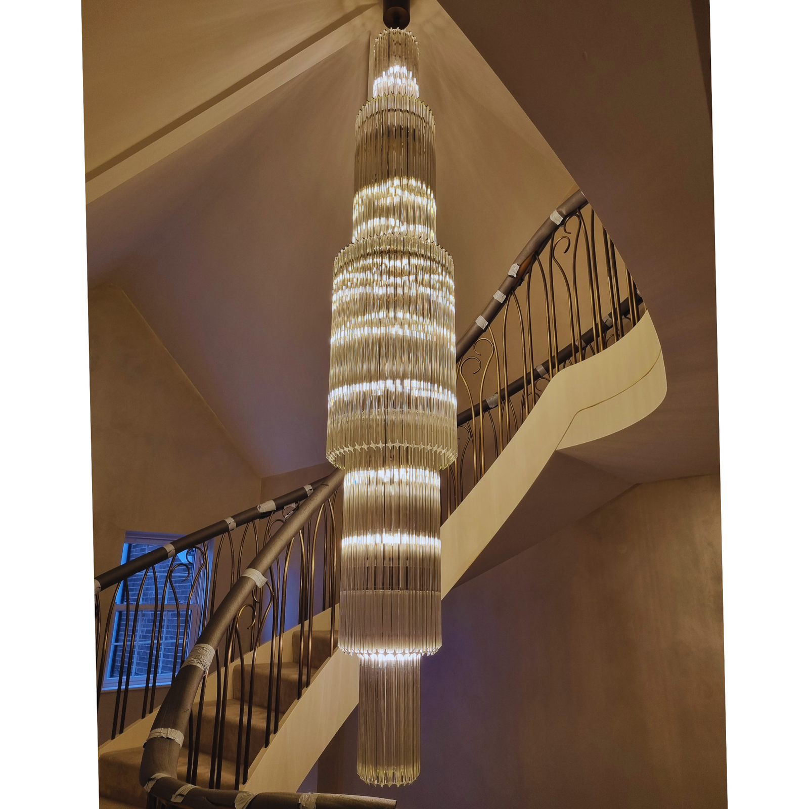 The Long Prism Chandelier illuminated in a grand staircase, highlighting its elegant design.